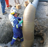 Worker in blue overalls wearing a hardhat installing a pump