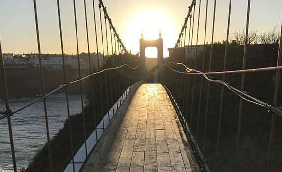 Visitors cross the suspension bridge to access the private holiday home.