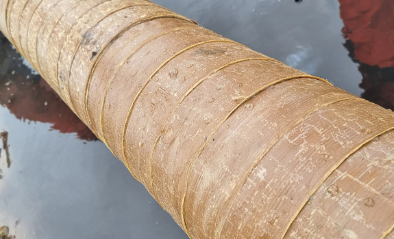 Brown fabric tape wrapped around a pipe over a puddle of water