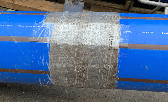 Close up view of a pipe joint on a blue water pipe protected with Denso Bore-Wrap.