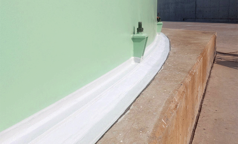 A white polyurethane topcoat applied around the base of a green storage tank.